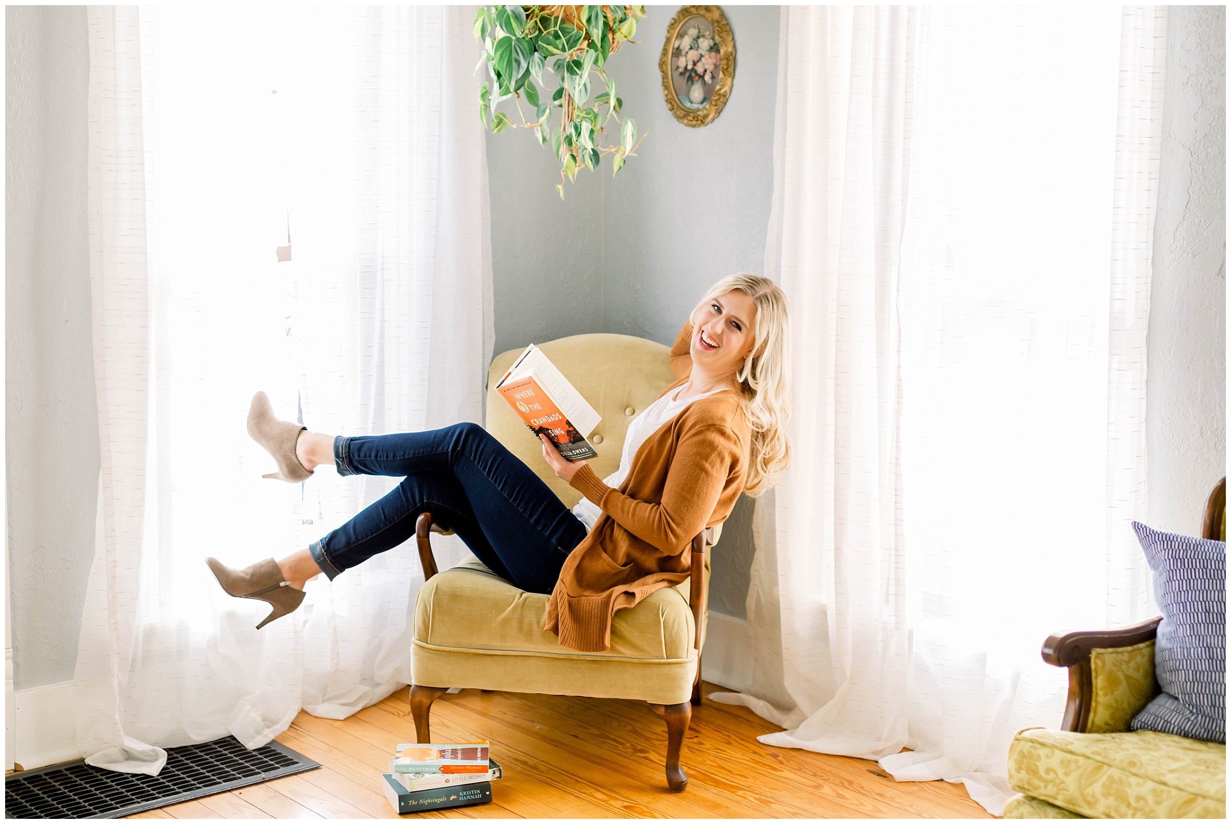 Woman sitting on chair laughing reading a book during a brand photography session