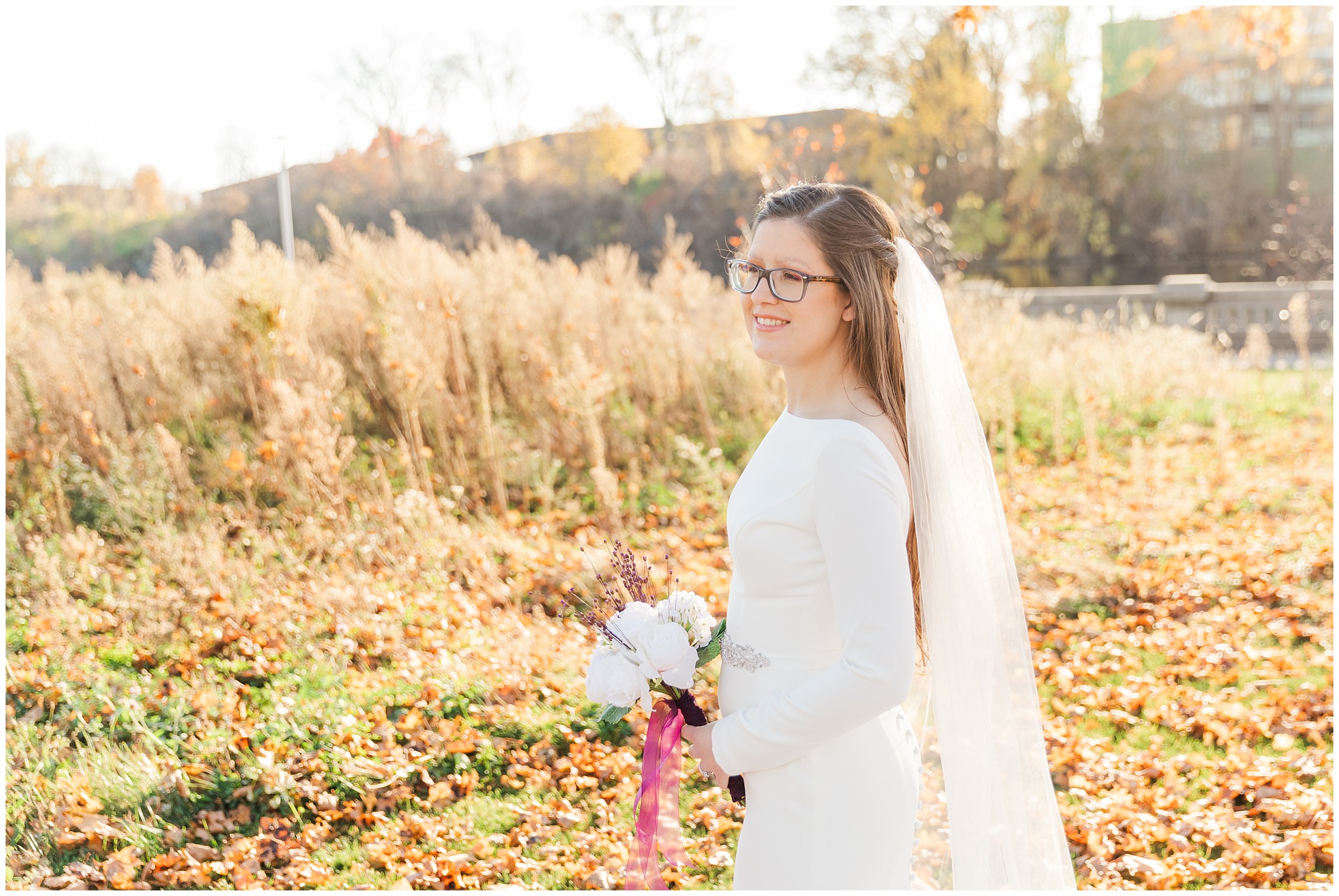 Bride smiling and holding a bouquet in a park during the fall