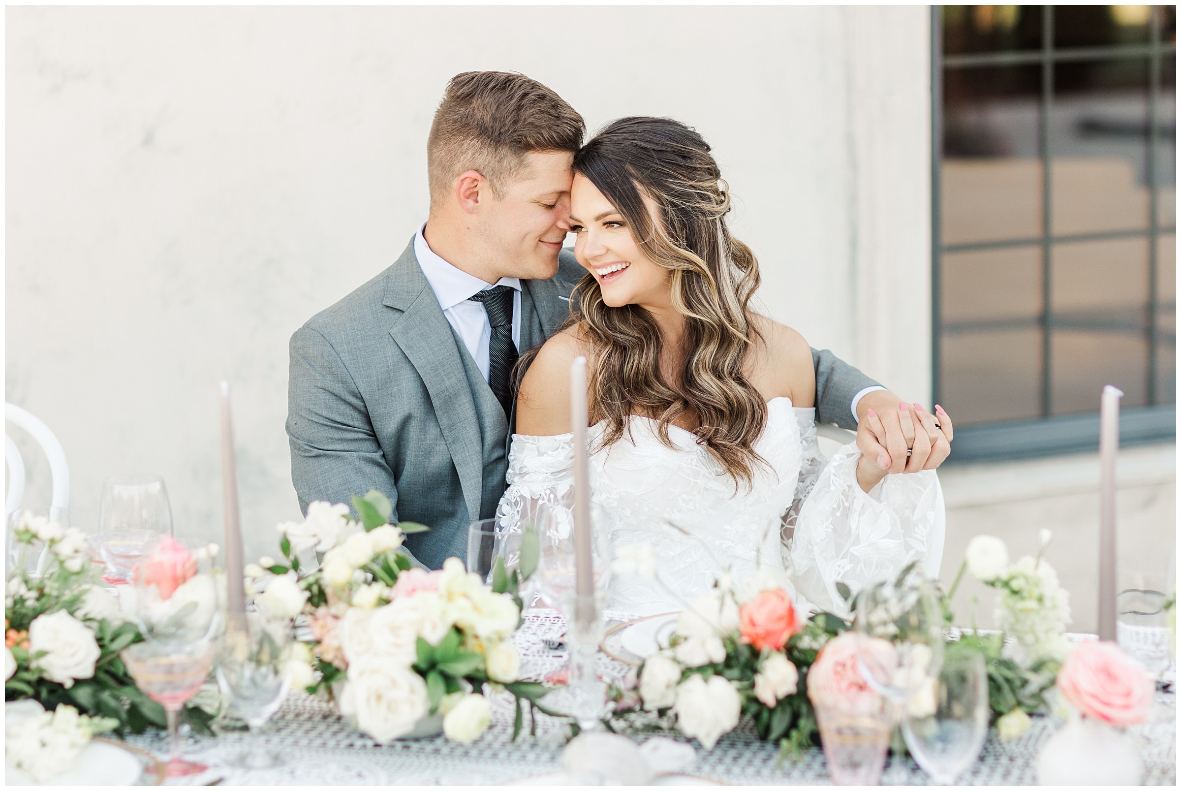 Bride and groom sitting together laughing surrounded by blush and yellow florals