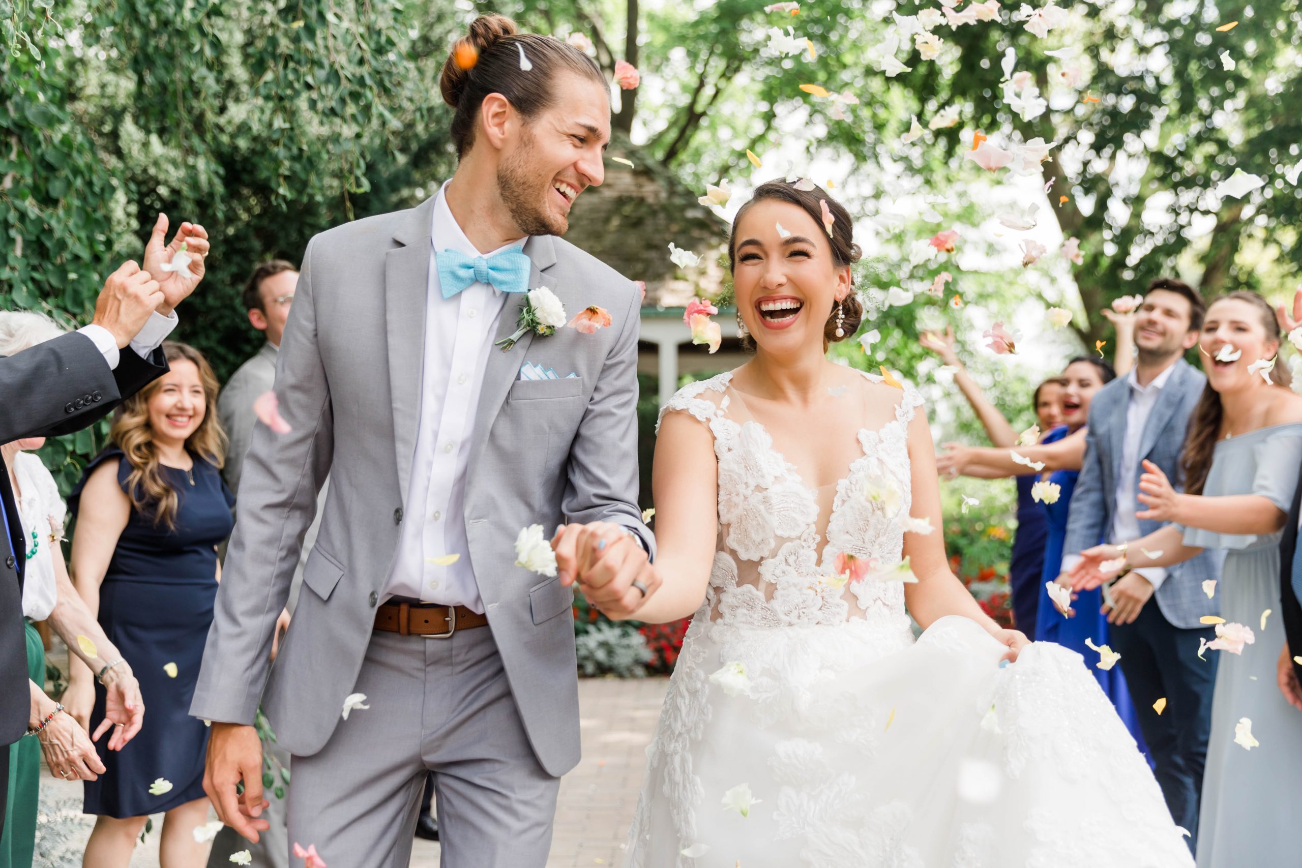 Bride and Groom smiling as petals rain around them in a garden